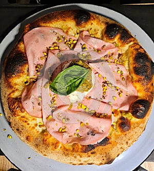pizza based on mozzarella, mortadella and cream and pistachio flakes