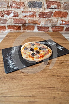Pizza on a blackboard with flour on a wooden table