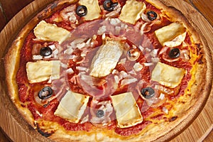A pizza with camembert cheese including bacon,black olives