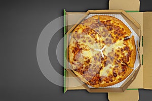 Pizza in a cardboard box on a black chalkboard background. Space for text
