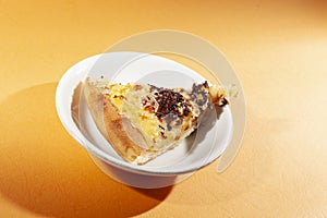 Pizza on ceramic plate, with cheese and chocolate sprinkles, on orange background