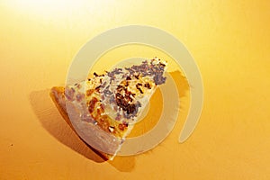 Pizza, with cheese and chocolate sprinkles, on orange background