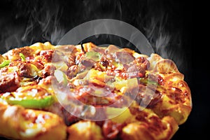 Pizza with cheese ham bacon and pepperoni on isolated black background with hot steaming smoke. Food and cooking concept. Lunch