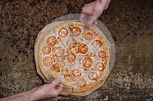 Pizza with cheese and tomatoes with copy space on an unusual brutal metal background with rust. Two people take slices of pizza