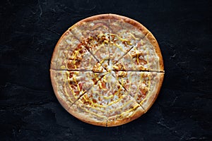 Pizza with chicken, cheese and tomatoes on a black stone background. Top view