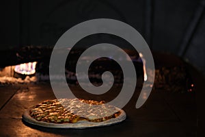 Pizza in clay oven with firewoods on fire photo