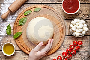 Pizza cooking ingredients. mozzarella, tomatoes, basil, olive oil, spices. Work with the dough. Top view. Flat lay.