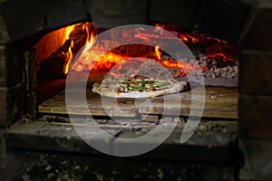 Pizza cooks in wood fired campsite oven