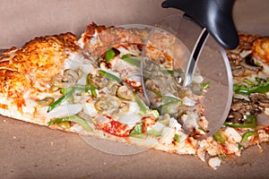Pizza cutter slicing through a pizza.