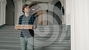 Pizza delivery boy holding boxes with pizza, young courier from food delivery service in modern office