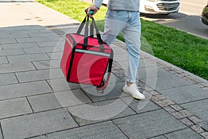 Pizza delivery man carries breakfast, lunch, dinner for consumers. Man of takeaway with red insulated food bag in hand