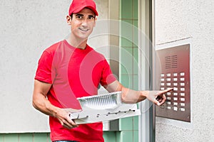 Pizza delivery man carrying boxes using the intercom