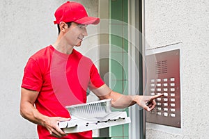 Pizza delivery man carrying boxes using the intercom