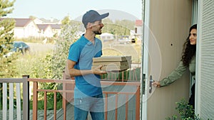 Pizza delivery man talking on mobile phone then giving boxes to happy woman customer