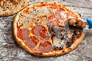 Pizza with different toppings. Italian pizza with different sorts of cheese, vegetables and meat on old wooden background close up