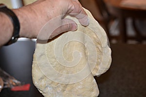 Pizza Dough being pinched to make thin in center photo