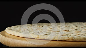 A pizza dough is rotating on dark background