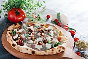 Pizza with dried tomatoes, mozzarella, sausage and rocket