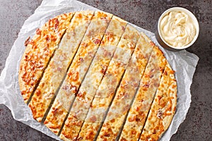 Pizza Garlic Fingers with mozzarella cheese, bacon and herbal butter and Donair Sauce close-up on paper. horizontal top view photo