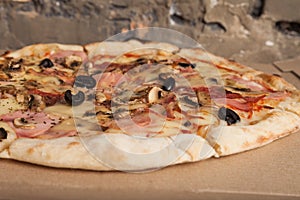 Pizza with ham, black olives, ham, spices. Italian pizza. Home made food. Concept for a tasty and hearty meal, lunch.