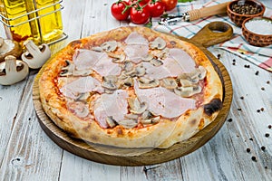 Pizza with ham and mushrooms on white wooden table