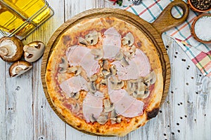 Pizza with ham and mushrooms on white wooden table