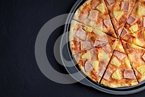 Pizza hawaii on dark stone background.