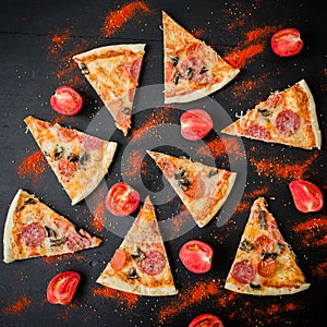 Pizza with ingredients on dark table. Pattern of pizza slices and tomato. Flat lay, top view.