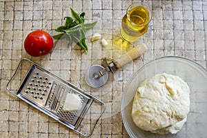 Pizza ingredients and fresh dough with cutter