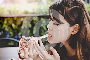 Pizza look so yummy or delicious food. Charming beautiful asian woman is eating pepperoni pizza and sticky mozzarella cheese.