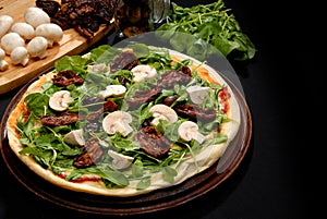 Pizza made of greens and mushrooms served on the round wooden tray