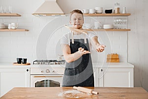 Pizza maker cook man in apron throws dough on light kitchen background