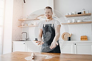 Pizza maker cook man in apron throws dough on light kitchen background