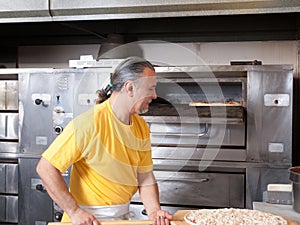 Pizza Maker puts a Fresh Pizza in the oven