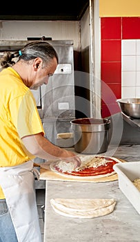 Pizza Maker puts mozzarella cheese on a pizza