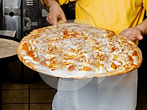 Pizza Maker removes a Fresh Pizza from the oven