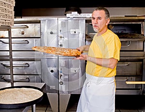 Pizza Maker removes a Fresh Pizza from the oven