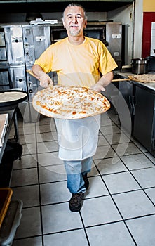 Pizza Maker removes a Fresh Pizza from the oven