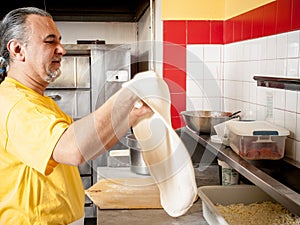 Pizza Maker twirls a Fresh Pizza dough photo