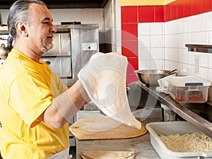 Pizza Maker twirls a Fresh Pizza dough photo