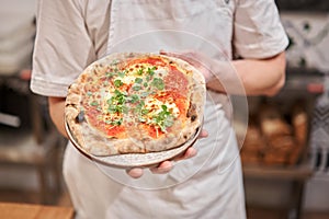 Pizza Margarita. Baked tasty margherita pizza in Traditional wood oven in Neapolitan restaurant, Italy.