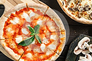 Pizza Margherita with cheese, tomatoes and basil on dark wooden background. Vegetarian pizza, top view, close up