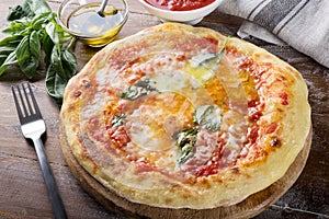 Pizza margherita, mozzarella, basil, tomato and olive oil on wooden background.