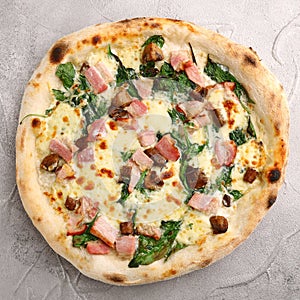 Pizza with meat, mushrooms and spinach close up on gray concrete background. italian pizza top view