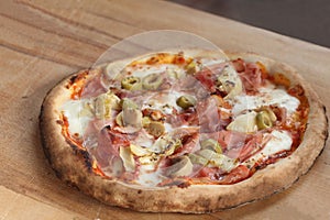 Pizza with mozzarella cheese, ham, olives on a wooden table with copy space for your text