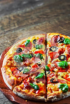 Pizza with Mozzarella cheese, ham, pepper, olive, meat, Tomato sauce, Spices and Fresh Basil. Italian pizza on wooden