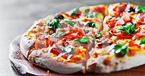 Pizza with Mozzarella cheese, ham, pepper, olive, meat, Tomato sauce, Spices and Fresh Basil. Italian pizza on wooden