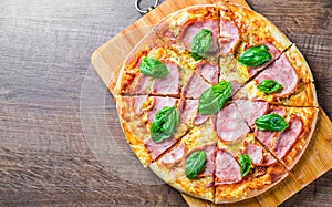 Pizza with Mozzarella cheese, ham, tomato sauce, pepper, Spices and Fresh basil. Italian pizza on wooden table