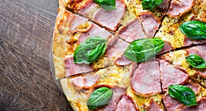 Pizza with Mozzarella cheese, ham, tomato sauce, pepper, Spices and Fresh basil. Italian pizza on wooden table