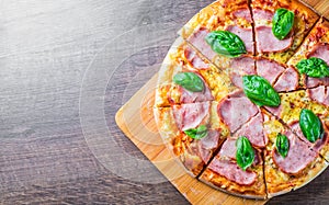 Pizza with Mozzarella cheese, ham, tomato sauce, pepper, Spices and Fresh basil. Italian pizza on wooden table